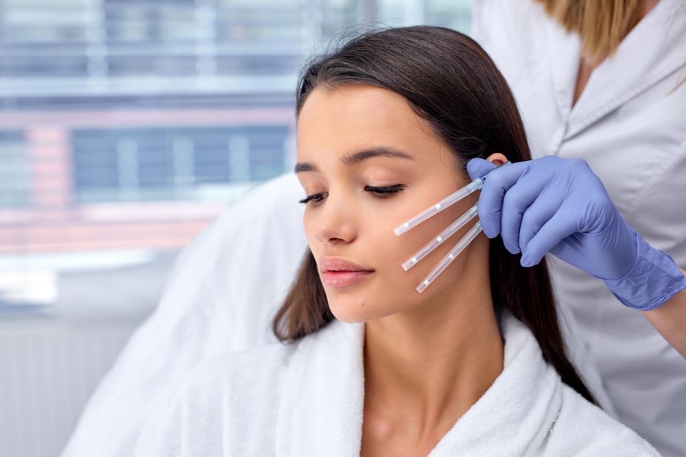 Woman receiving a facial treatment with serums in a spa setting, showcasing skincare procedures and beauty therapy.