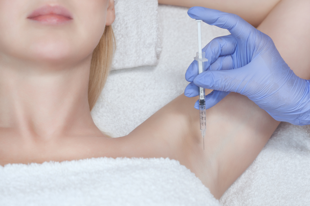 Close-up of a healthcare professional in blue gloves administering an injection in the underarm area of a patient during a medical procedure, highlighting the importance of safe and effective treatments.